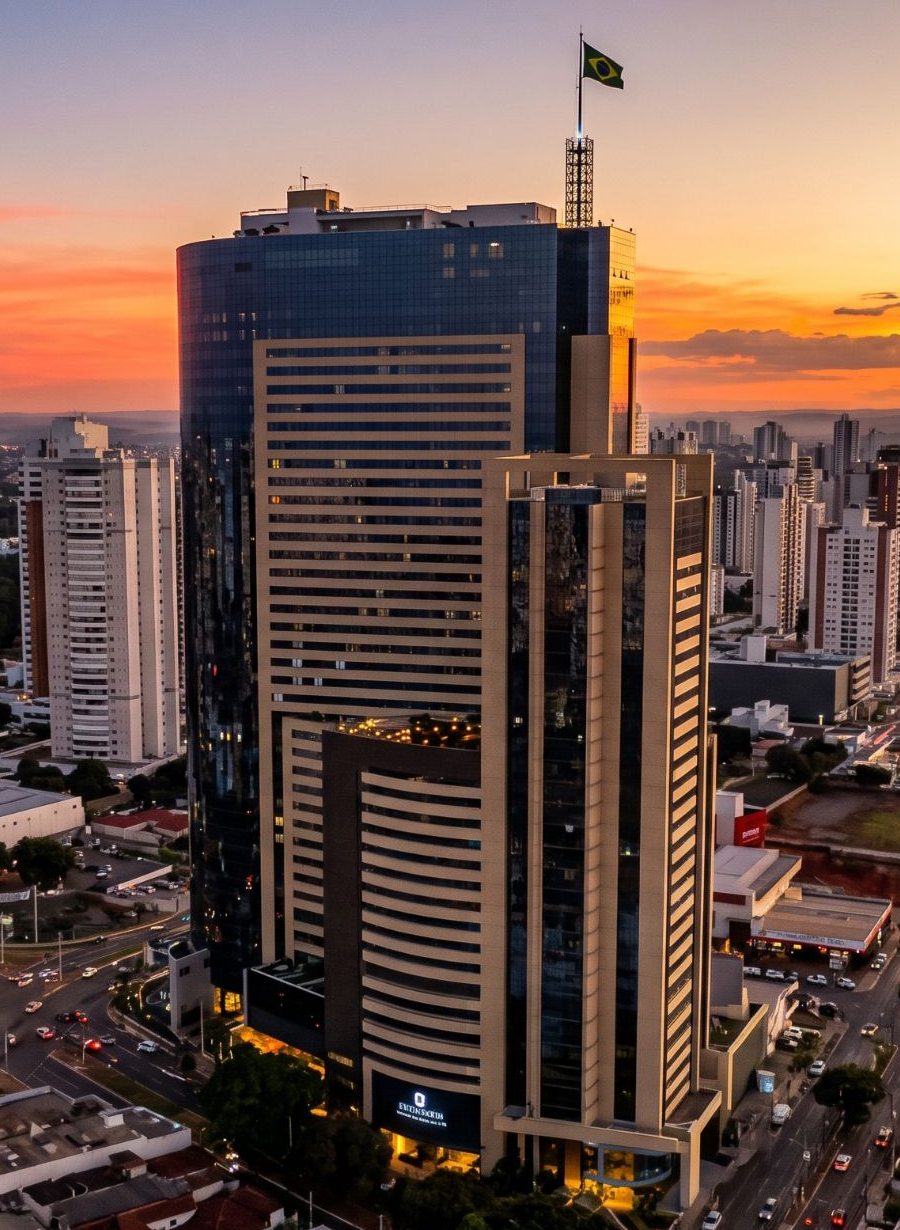 Edifício Orion visto do alto ao pôr do sol, com a bandeira do Brasil no topo